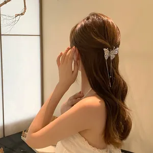 Elegant butterfly rhinestone hair claw clip with tassels worn in a half-up hairstyle