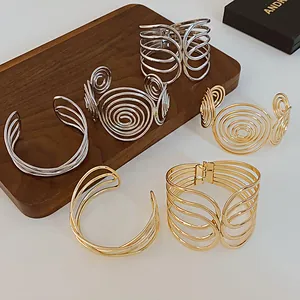Minimalist multi-layer spiral metal cuff bracelets in gold and silver finishes.