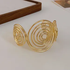 Close-up of golden minimalist spiral open cuff bracelet showing swirl detail