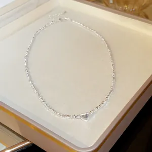Detailed view of a silver irregular textured necklace with a polished heart pendant