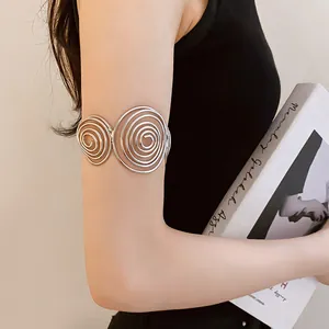 Close-up of minimalist silver spiral arm cuff worn on model arm against neutral background