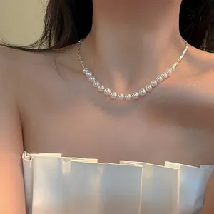 Detailed view of a silver pearl necklace on model for a French retro style look