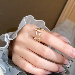 Close-up detail of a delicate gold leaf open ring worn on a hand with ruffled white sleeves