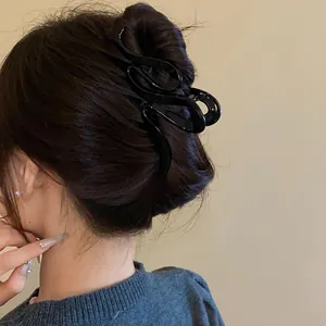 Detailed view of a stylish black wavy twisted acrylic hair claw clip used for a bun