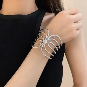 Close-up of a stylish multi-layer silver-toned cross-over open cuff bracelet on wrist.