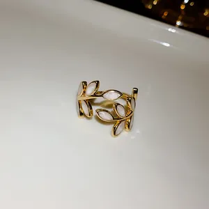 Detailed view of an elegant gold leaf open ring featuring white pearlescent enamel leaves