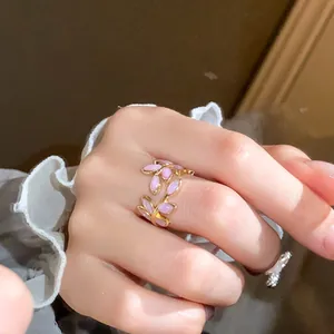 Detailed macro view of an elegant gold leaf open ring featuring pink marquise stones worn on finger