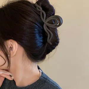 Macro view of a minimalist matte black wavy hair claw clip securing a sleek bun