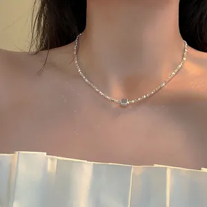 Detailed view of silver irregular beaded necklace featuring a geometric cube pendant.