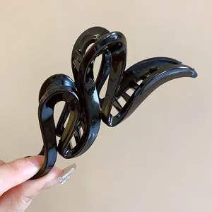 Close-up of a minimalist black wavy acrylic hair claw clip with an elegant curved design