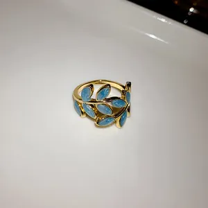 Detail shot of an elegant gold leaf open ring with blue glitter enamel finish jewelry