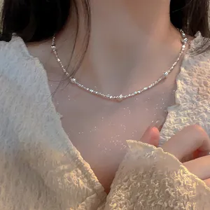 Close-up of a silver irregular bead necklace worn on a woman's collarbone