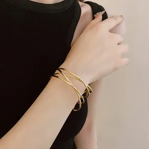 Close-up of minimalist gold multilayer crisscross open bangle bracelet on wrist
