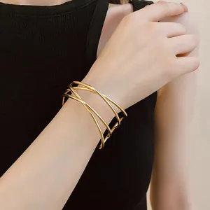 Detailed view of an elegant multi-layer criss-cross gold cuff bracelet worn on a wrist