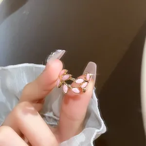 Close-up detail of a sweet pink leaf open ring worn on a finger with a white ruffle sleeve