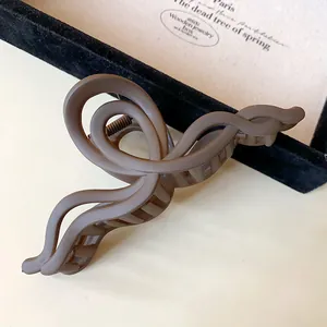 Macro detail of a matte mocha brown wave twisted acrylic hair claw clip.