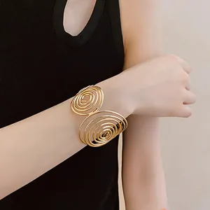 Close-up of a minimalist gold multi-layer spiral open cuff bracelet worn on a wrist
