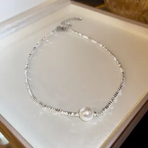 Close-up of silver irregular beaded necklace featuring a central pearl in a jewelry box