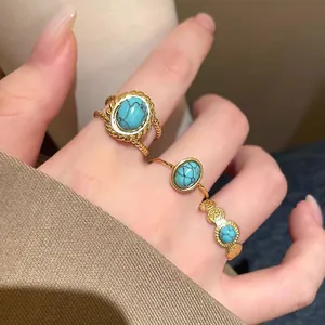 Close-up of gold-plated turquoise rings on model's hand, vintage style jewelry.