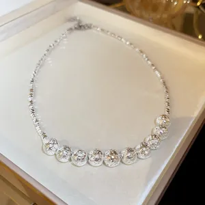Macro view of a silver textured metal bead necklace on a jewelry display cushion