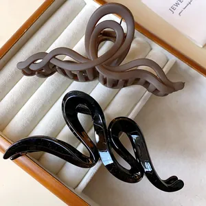 Close-up detail of wavy twisted acrylic hair claws in matte brown and glossy black