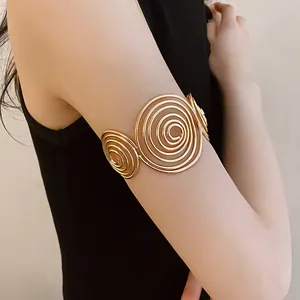 Detail view of a minimalist gold spiral open arm cuff worn stylishly on the upper arm.