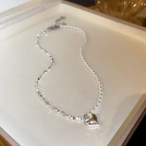 Close-up of French vintage necklace featuring heart pendant and irregular pearls