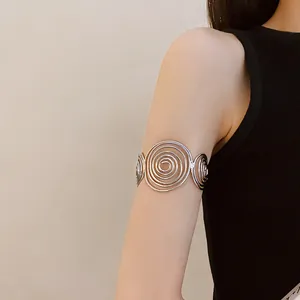 Close-up detail view of a minimalist silver metal spiral armlet worn on the upper arm.