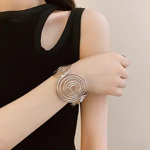 Close-up detail of a minimalist silver spiral cuff bracelet on a female model's wrist