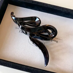 Detailed view of a glossy black wavy acrylic hair claw clip for elegant hair styling