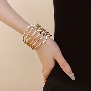Close-up of a multi-layer gold metal open bracelet on a wrist with a minimalist style