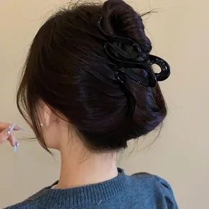 Close-up detail of an elegant black wavy acrylic hair claw clip worn on dark hair bun
