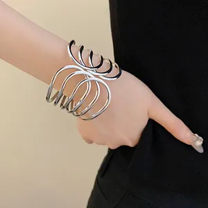 Close-up of a stylish silver multi-layer wavy open cuff bracelet on a female wrist.