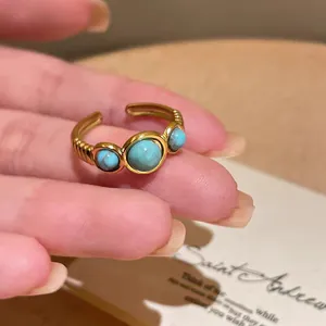 Detailed close-up showing a vintage gold plated open ring with three round turquoise stones.