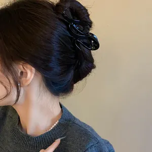 Detail of a black acrylic wavy hair claw clip worn in a stylish updo on a model.