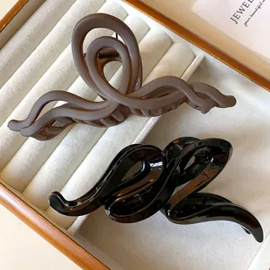 Close-up detail of wave twisted hair claw clips in matte brown and glossy black.