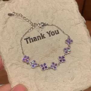 Detail van sprankelende paarse zirkoon bloemhangers aan een fijne zilveren armband