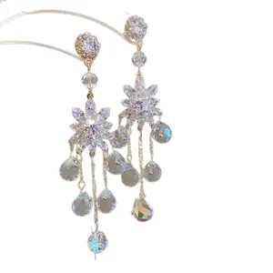 Eleganti orecchini pendenti in cristallo floreale con gocce d'acqua su sfondo bianco.