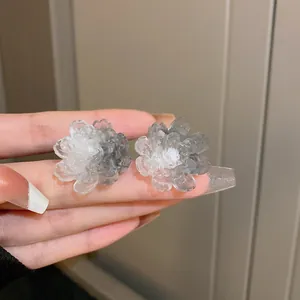 Close-up of semi-transparent floral stud earrings with gradient gray petals