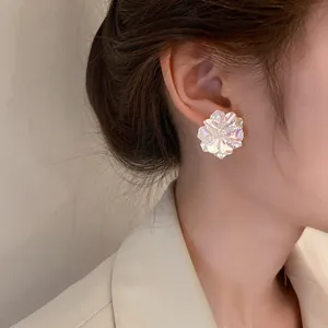 Close-up of elegant pearlescent floral stud earrings with silver needles on ear