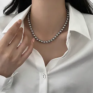 Vista dettagliata di un'elegante collana di perle grigie indossata da una modella.