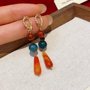 Dettaglio di orecchini vintage stile etnico con perle di pietra colorate e pendenti