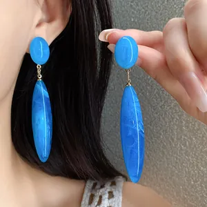 Detalle de elegantes pendientes colgantes de acrílico azul vintage con textura de mármol.