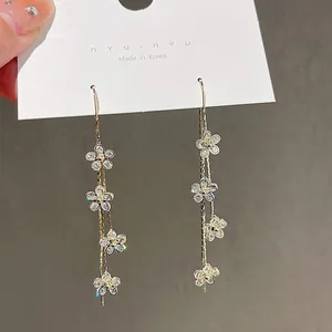 Dettaglio ravvicinato di orecchini pendenti a fiori su un cartoncino bianco liscio