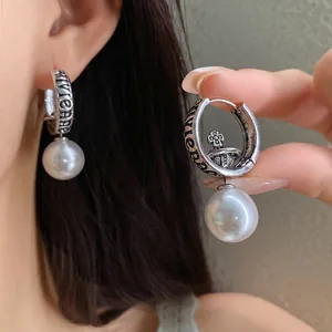 Retro silver-toned hoop earrings featuring planet orb design and elegant large white pearl drop