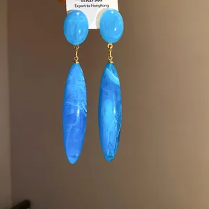 Primer plano de pendientes de gota en acrílico jaspeado azul y oro