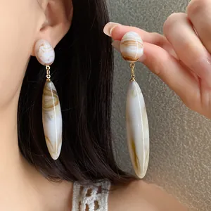 Detalle de elegantes pendientes de gota de acrílico con patrón de mármol vintage.