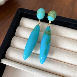 Detalle de pendientes de gota azules vintage con elegante textura acrílica jaspeada.