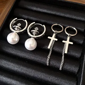 Silver-toned hoop earrings set with cross and pearl orb charms in jewelry tray