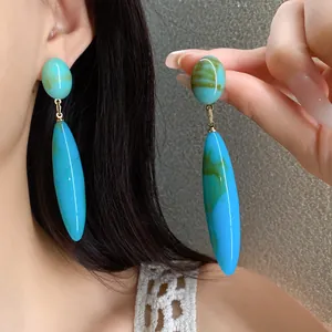 Primer plano de los pendientes vintage de gota en acrílico azul mármol en la oreja